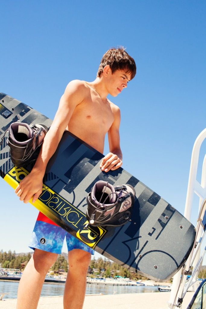 Shirtless Hayes Grier holds wakeboard.